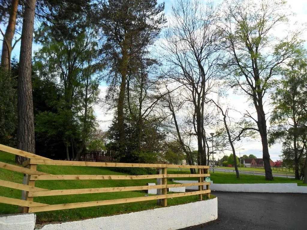 a wooden fence in a park with trees at Smithton Hotel in Inverness