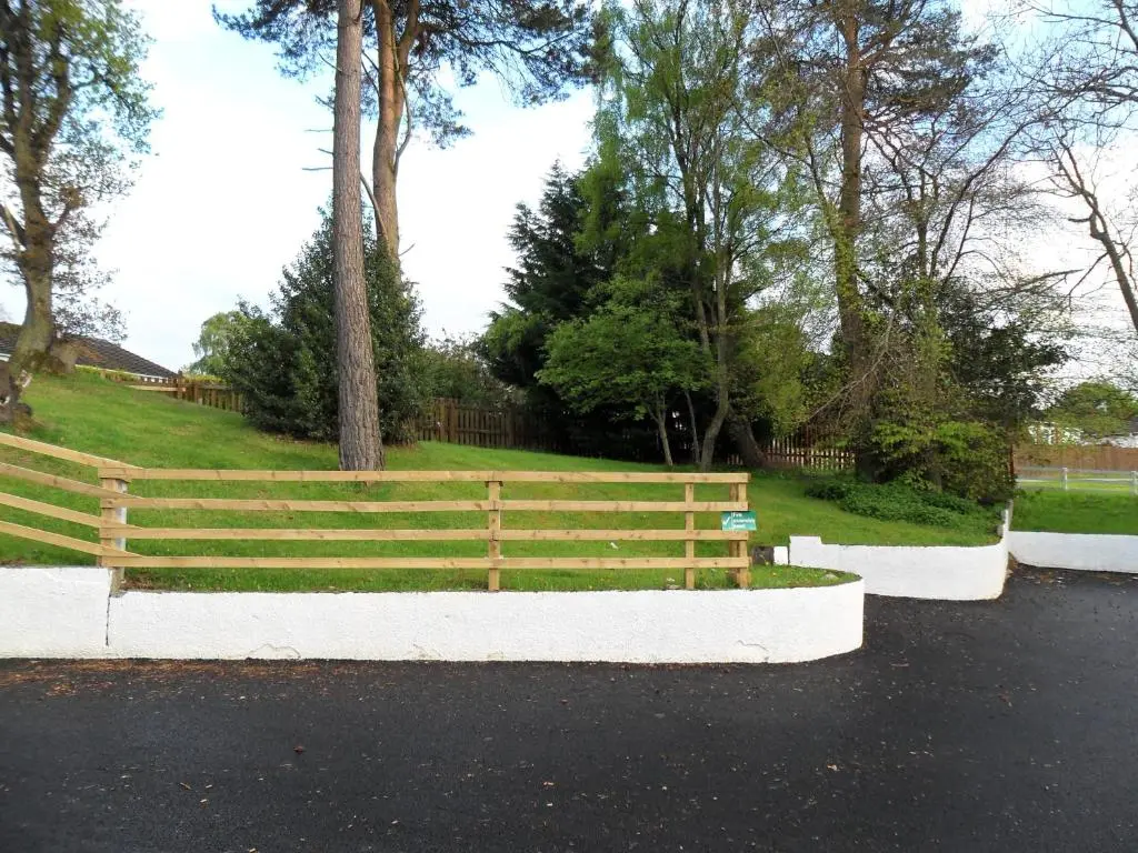 a wooden fence in front of a field with trees at Smithton Hotel in Inverness