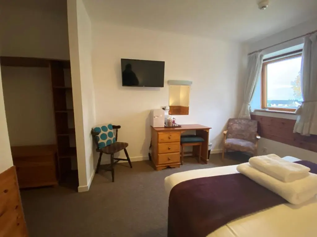 a hotel room with a bed and a desk and a window at Smithton Hotel in Inverness