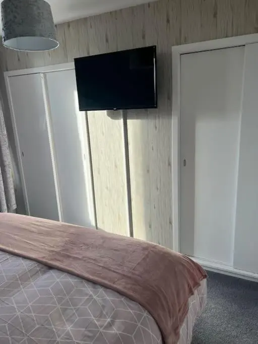 a bedroom with a bed and a flat screen tv on the wall at GWR Dickson's House, NC500, Wick in Wick