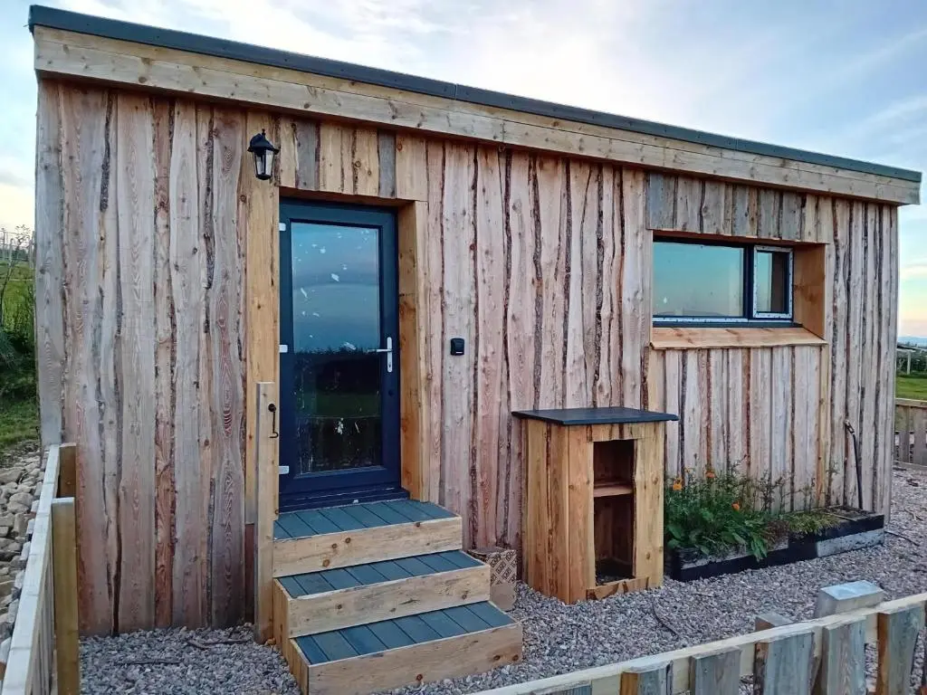 a wooden tiny house with a door and stairs at Honeysuckle Straw Bale Cabin