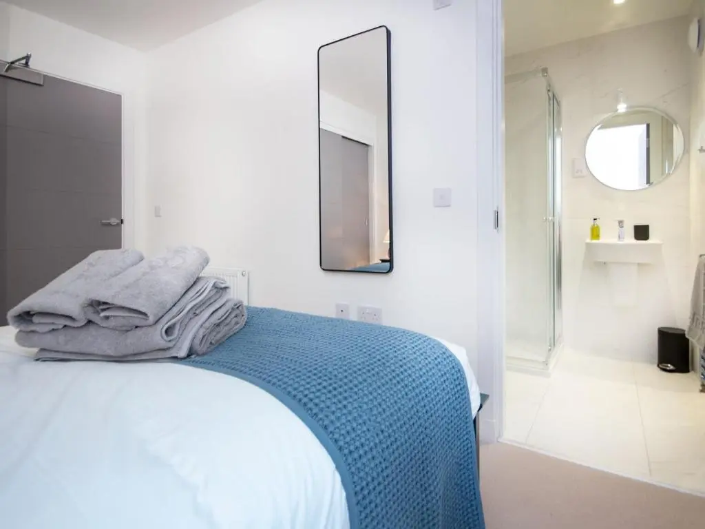 a white bedroom with a bed and a mirror at Caledonia View in Aviemore
