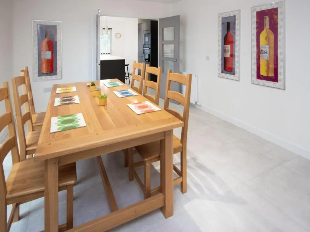 a wooden table and chairs in a room with paintings at Caledonia View in Aviemore