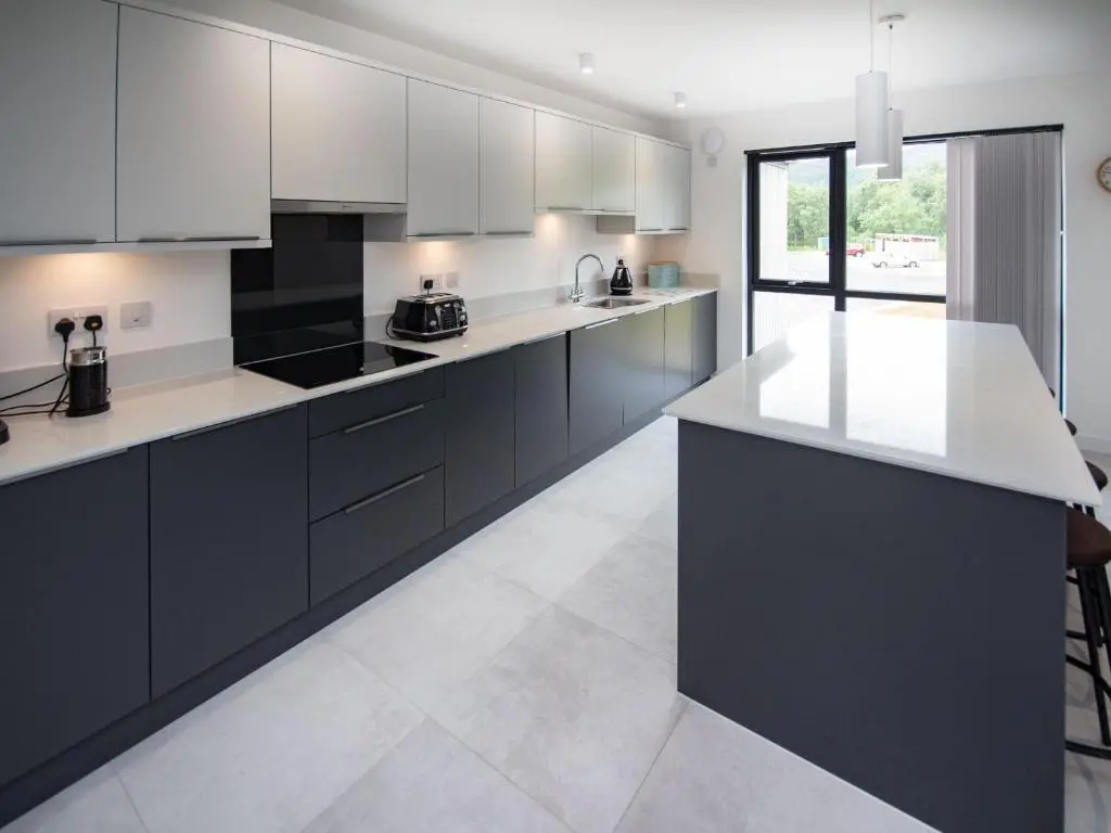a kitchen with black cabinets and white counter tops at Caledonia View in Aviemore