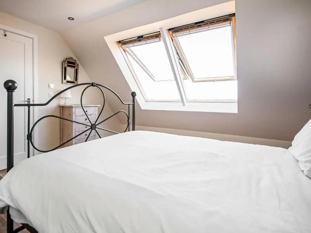 a bedroom with a bed and two windows at Y Bwthyn in Culbokie