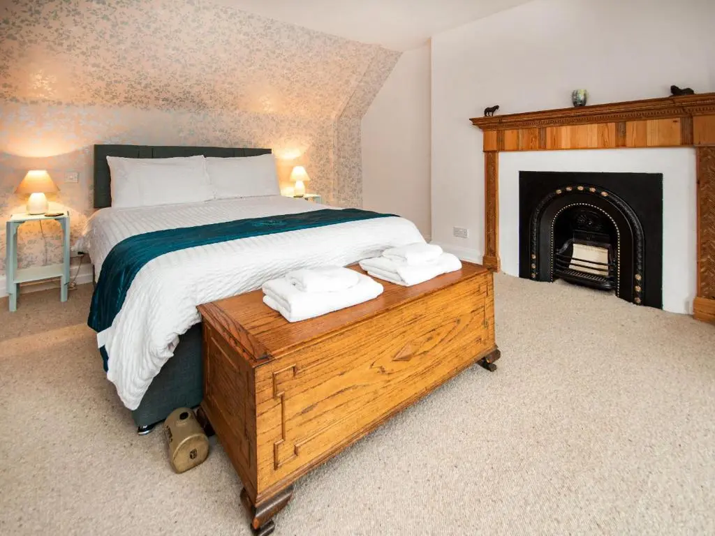a bedroom with a large bed and a fireplace at Solus Na Madainn in Tain