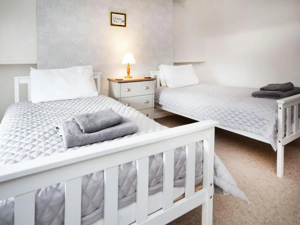 two beds in a bedroom with white walls at Solus Na Madainn in Tain