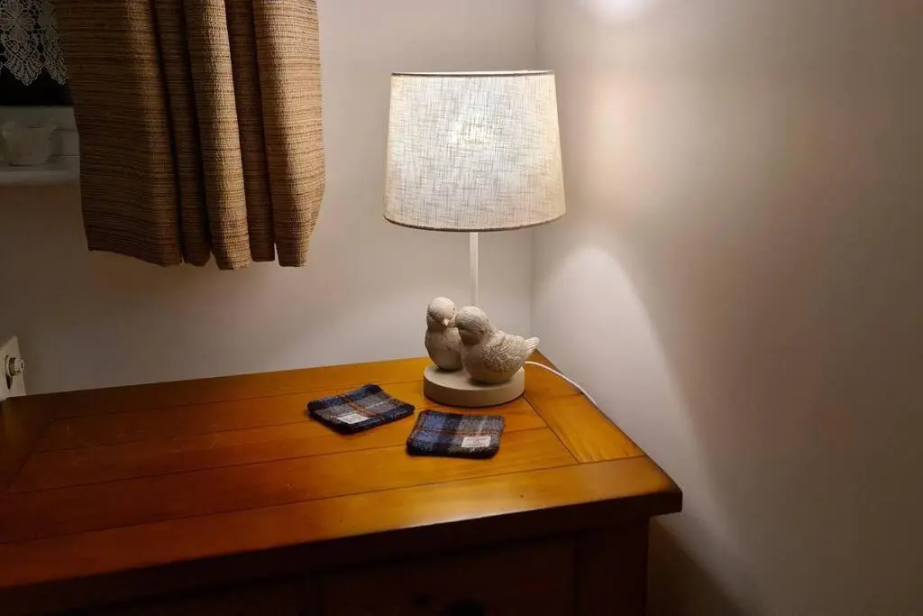a table with a lamp and a book on it at Northlea-Scottish style cottage in Inverness
