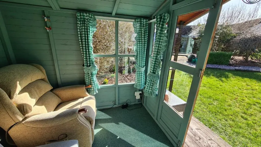 a screened in porch with a couch and a window at Northlea-Scottish style cottage in Inverness