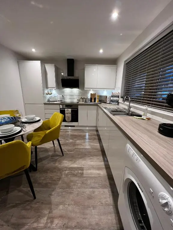 a kitchen with a table and yellow chairs and a dishwasher at Salt View in Cullen