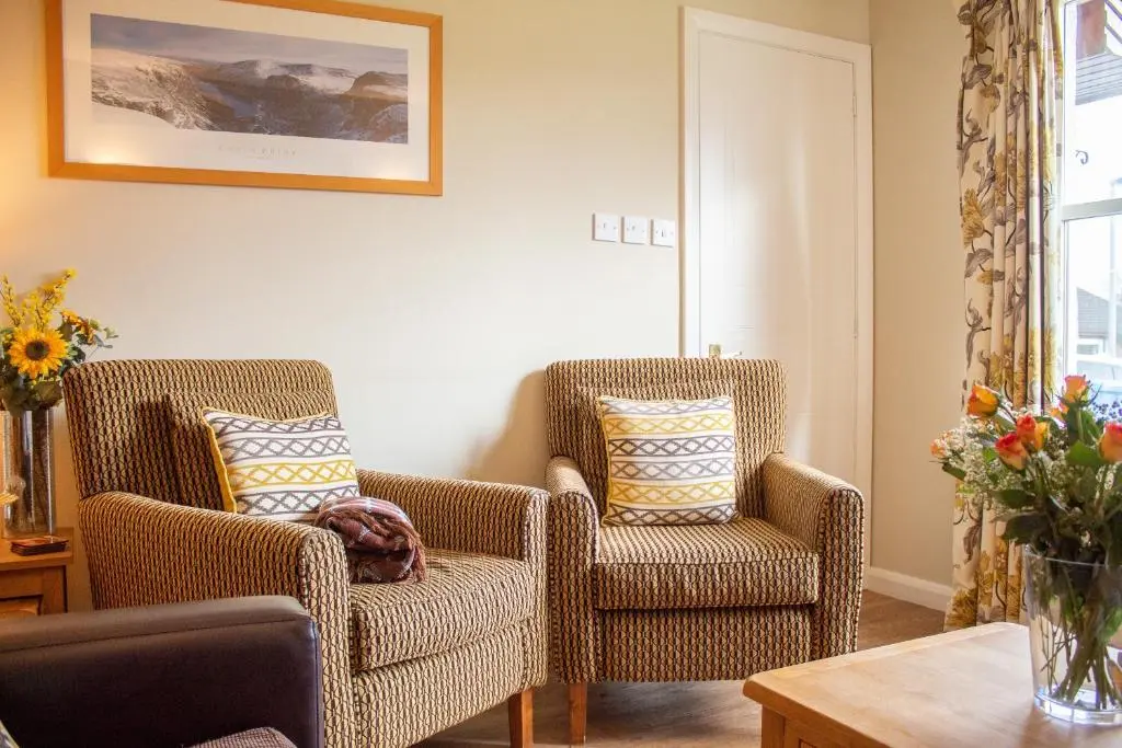 a living room with two chairs and a table at Pine Marten Cottage - Aviemore in Aviemore