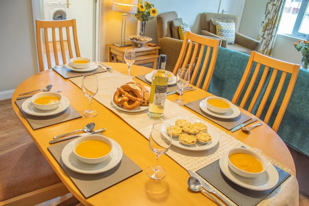 a wooden table with plates of food on it at Pine Marten Cottage - Aviemore in Aviemore