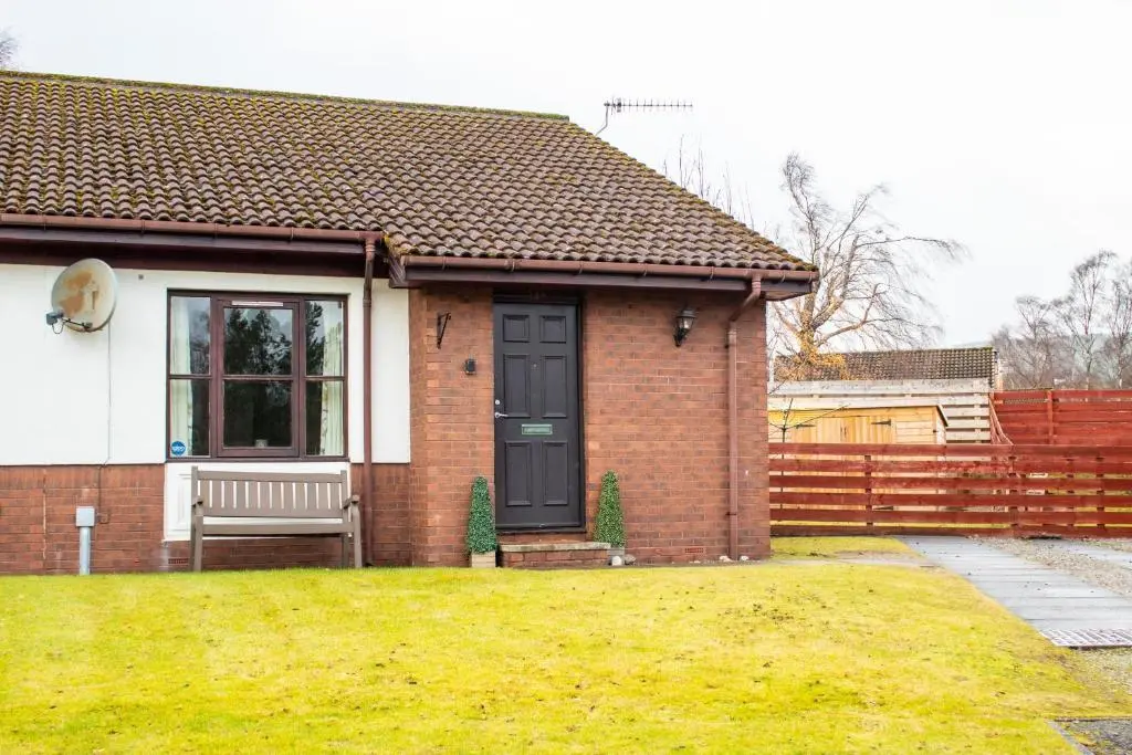 a small brick house with a black door at Pine Marten Cottage - Aviemore in Aviemore