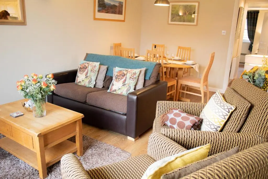a living room with a couch and chairs and a table at Pine Marten Cottage - Aviemore in Aviemore