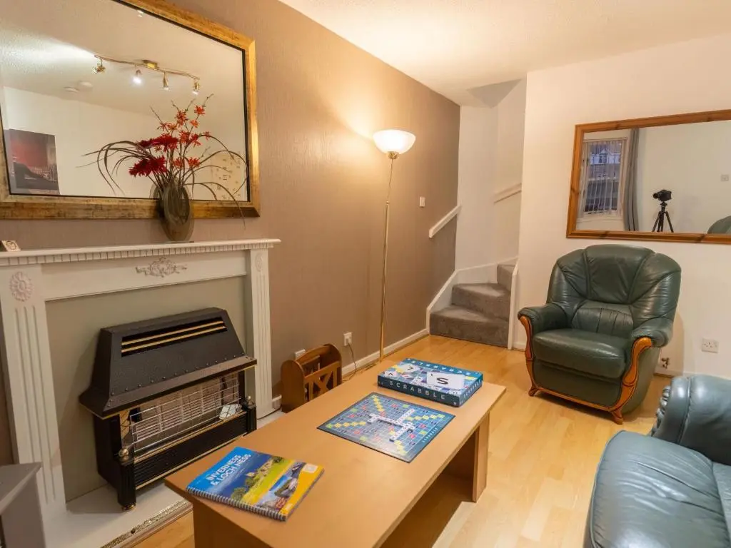 a living room with a fireplace and a chair at Villa Cedar House by Interhome in Inverness