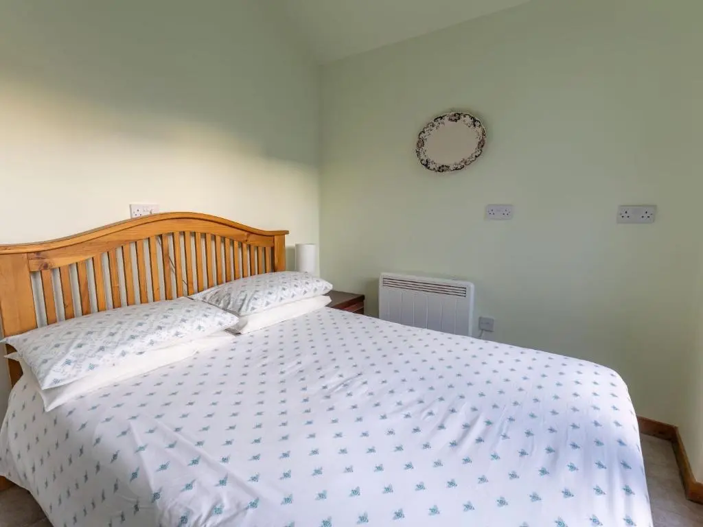 a bedroom with a white bed with a wooden headboard at Holiday Home Lodge Road by Interhome in Inverness