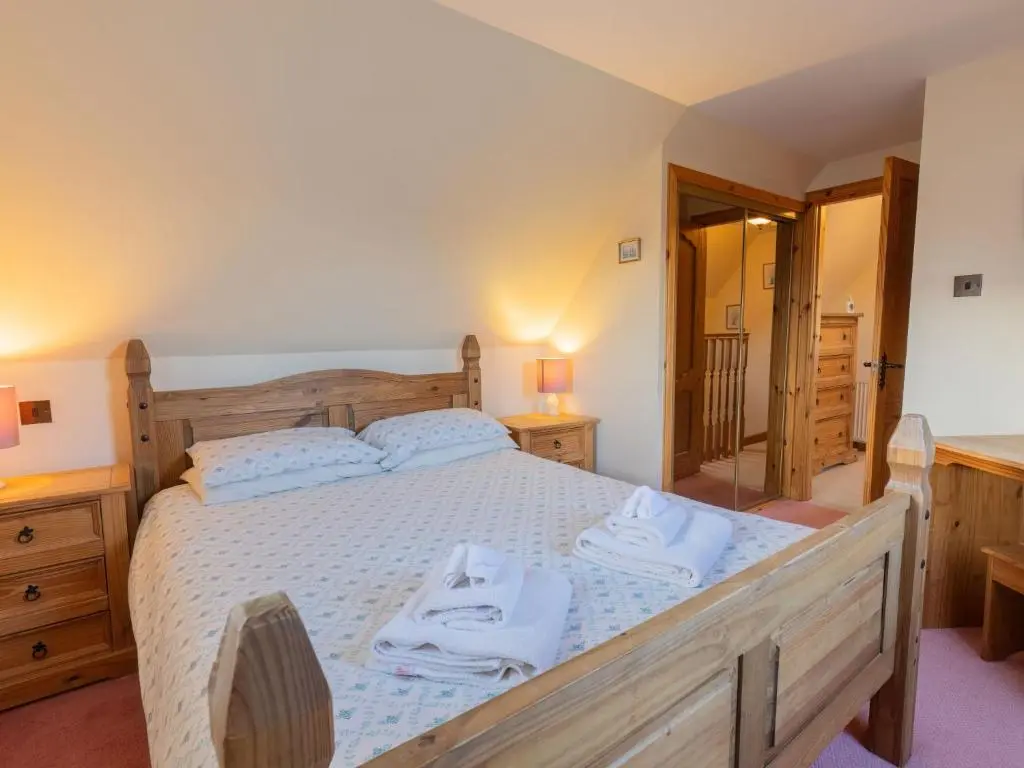 a bedroom with a large wooden bed with towels on it at Holiday Home Lodge Road by Interhome in Inverness
