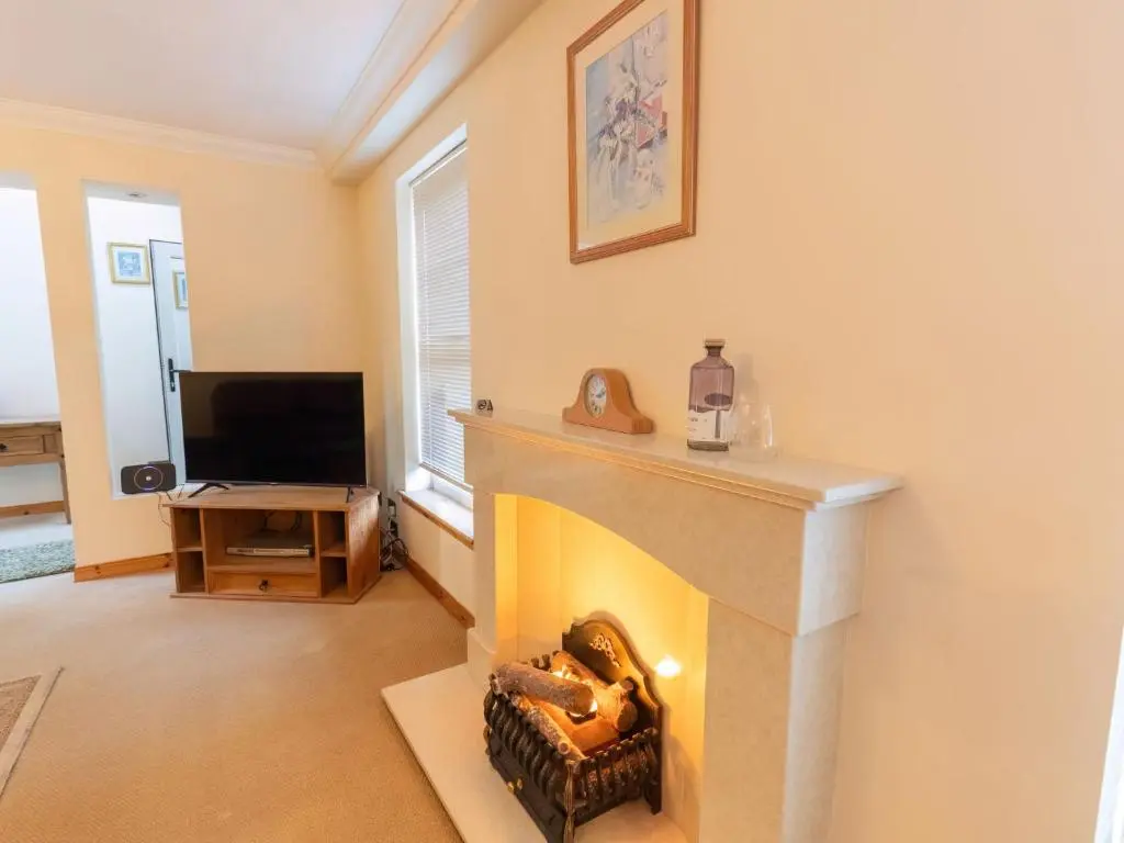 a living room with a fireplace and a tv at Holiday Home Lodge Road by Interhome in Inverness