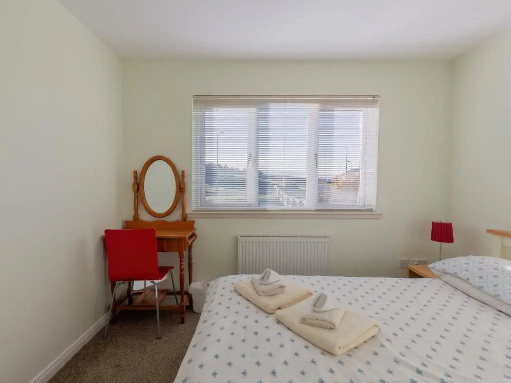 a bedroom with two beds and a chair and a mirror at Apartment Ash House by Interhome in Inverness