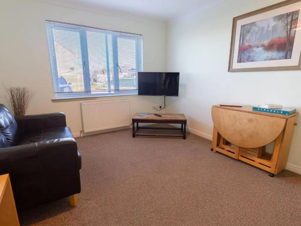 a living room with a couch and a tv and a table at Apartment Ash House by Interhome in Inverness