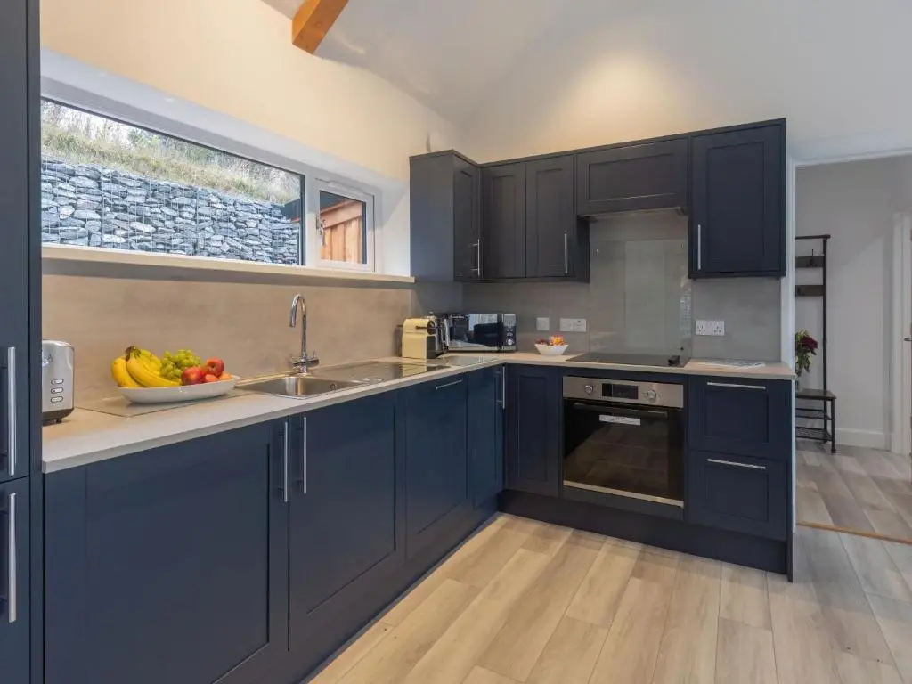 a kitchen with blue cabinets and a bowl of fruit on the counter at Holiday Home Loch View by Interhome in Balnain