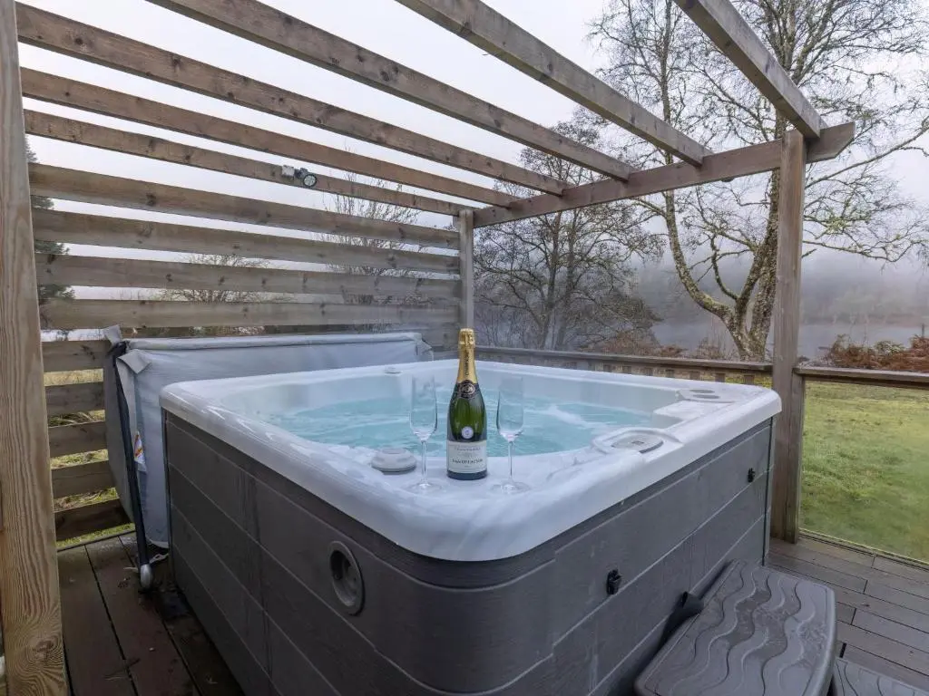 a hot tub with a bottle of wine in it at Chalet Lothlorien Lodge 4 by Interhome in Spean Bridge
