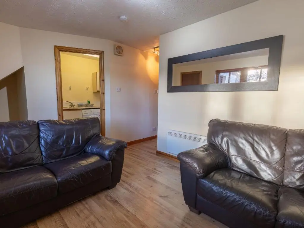 a living room with a leather couch and a mirror at Apartment Miller Heights by Interhome in Inverness