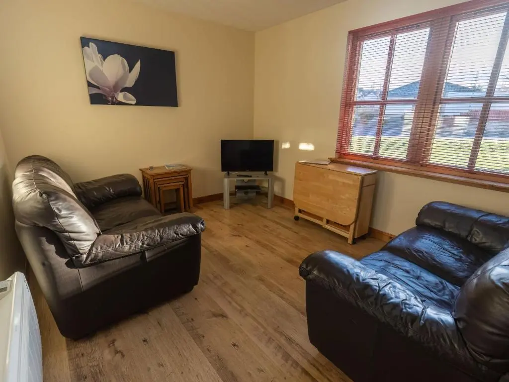 a living room with a leather couch and a television at Apartment Miller Heights by Interhome in Inverness