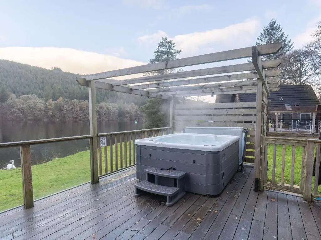 a hot tub on a deck with a pergola at Chalet Woodhaven by Interhome in Spean Bridge
