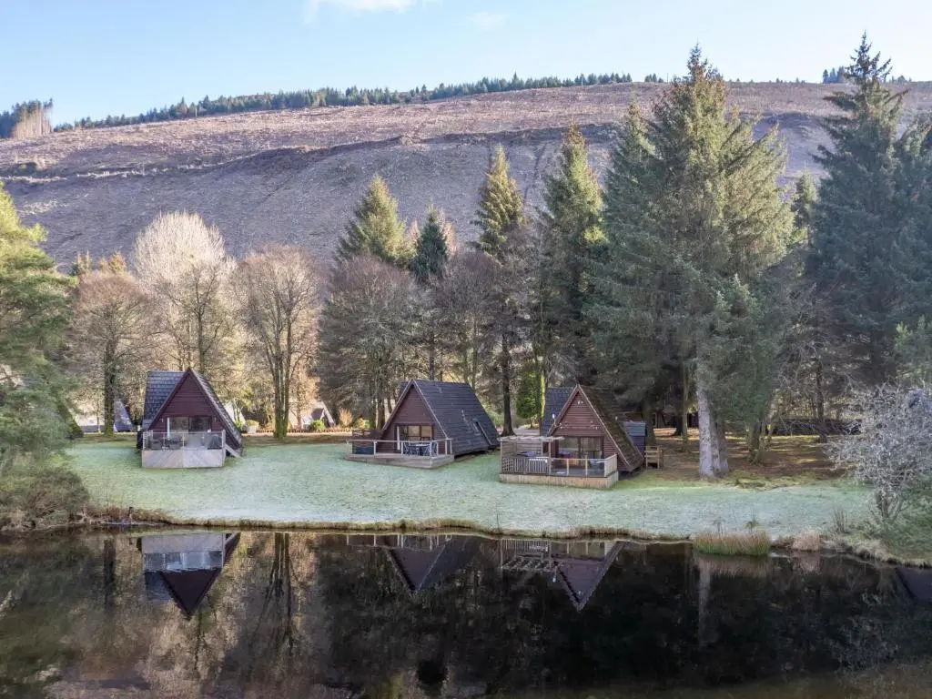 a group of cottages next to a body of water at Chalet Woodhaven by Interhome in Spean Bridge