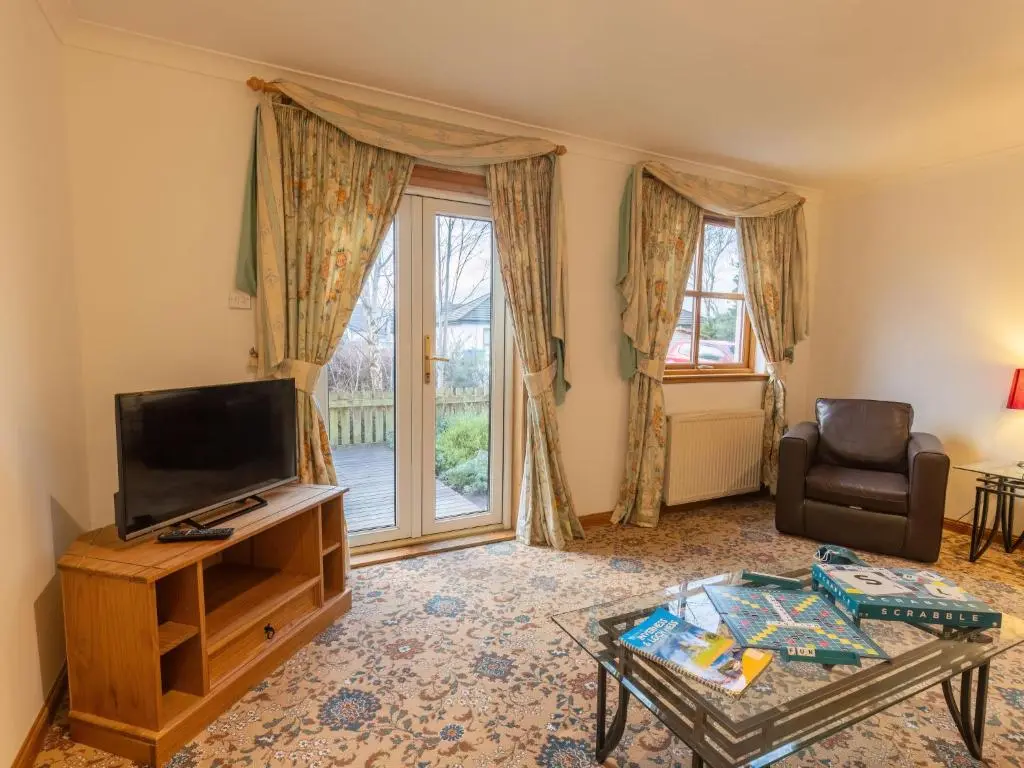 a living room with a flat screen tv and a table at Apartment Elm Grove by Interhome in Inverness