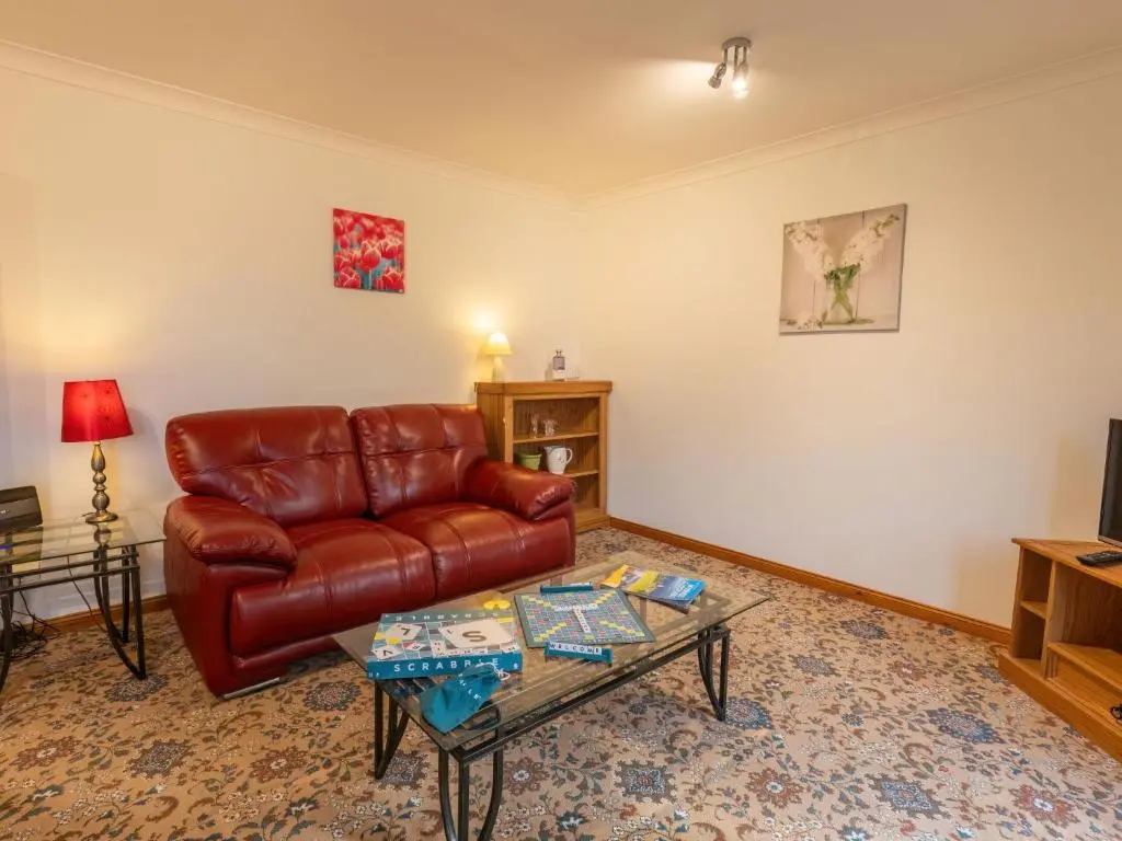 a living room with a leather couch and a coffee table at Apartment Elm Grove by Interhome in Inverness
