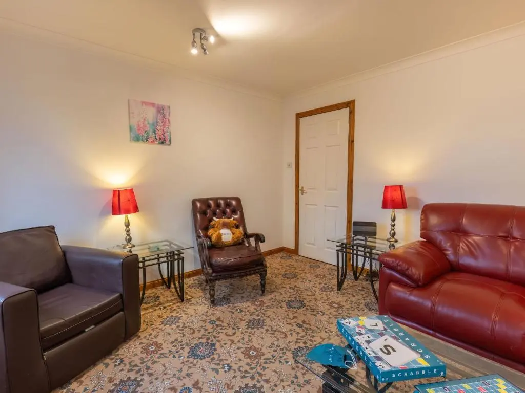 a living room with a leather couch and a chair at Apartment Elm Grove by Interhome in Inverness
