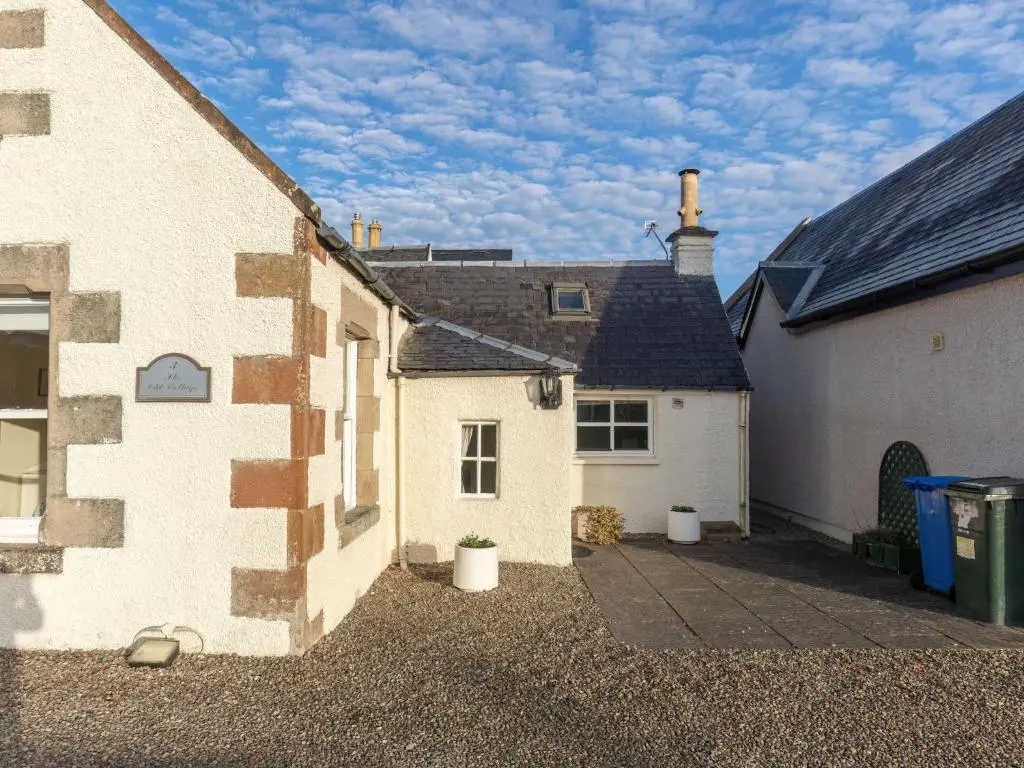 a white house with a driveway next to two buildings at Holiday Home Old Lodge by Interhome in Inverness