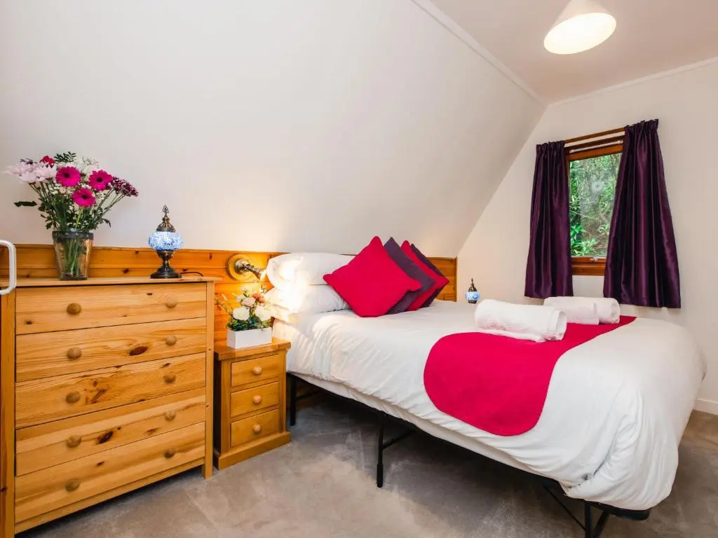 a bedroom with a large bed and a dresser at Chalet Rivendell by Interhome in Spean Bridge