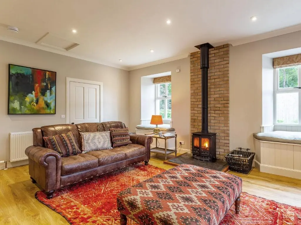 a living room with a leather couch and a fireplace at 1 Bed in Forres 78430 in Forres