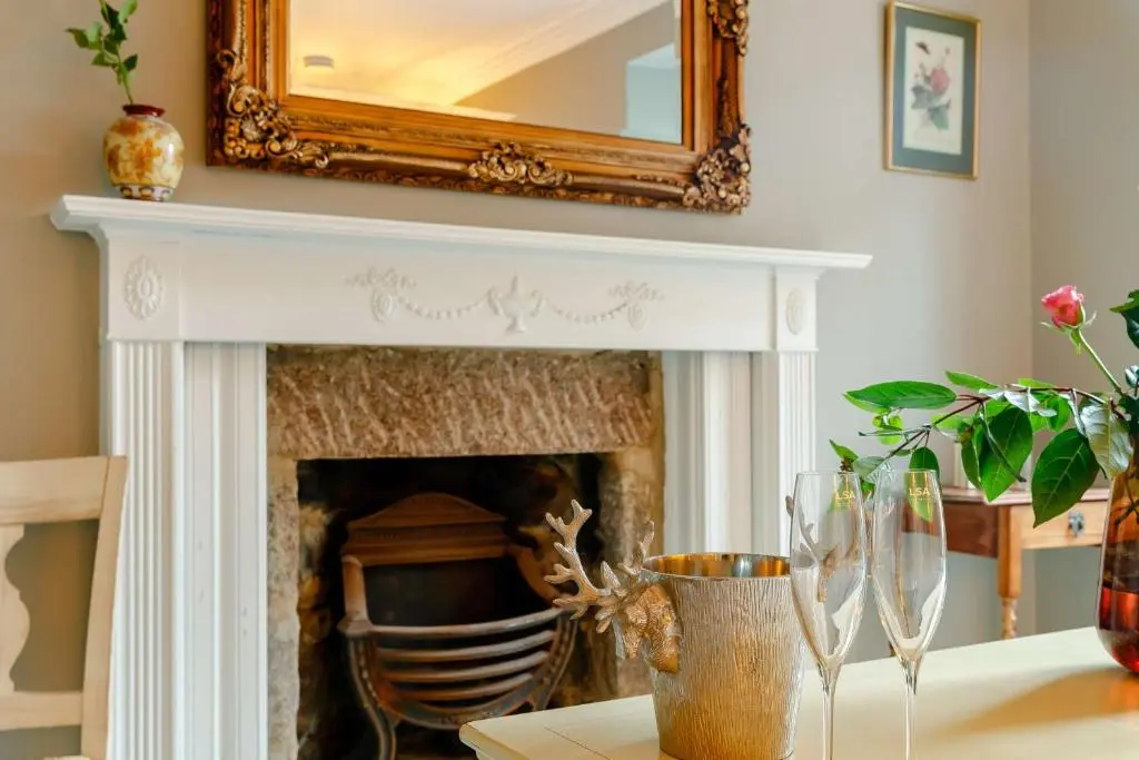 a fireplace with a mirror and wine glasses on a table at Manar House Ground Floor Luxury Apartment in Inverurie