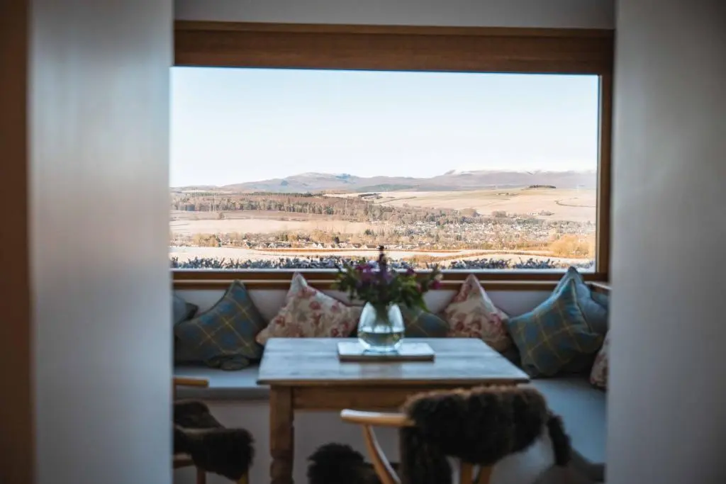 a room with a couch and a table with a window at Kinkell Cottage in Dingwall