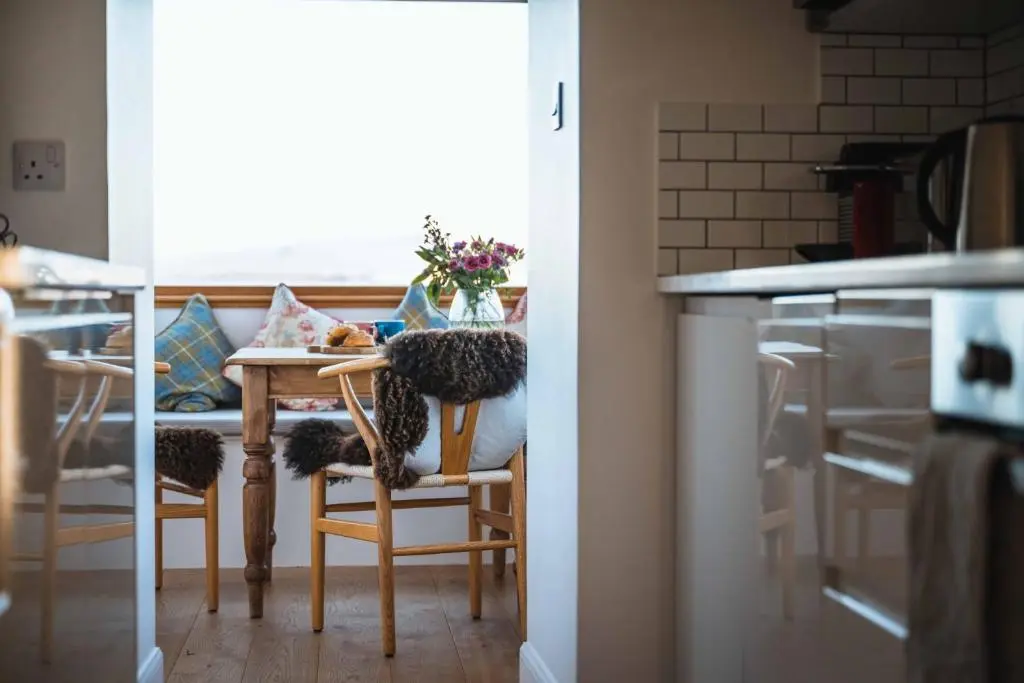 a kitchen with a table and chairs and a kitchen with a window at Kinkell Cottage in Dingwall