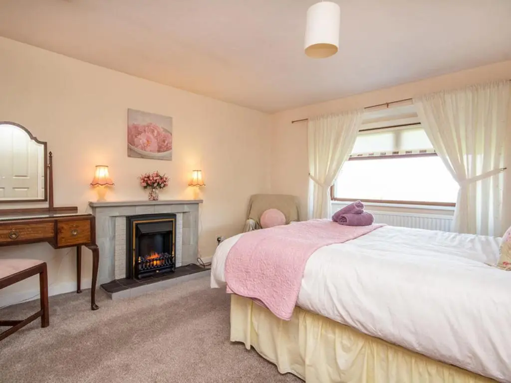 a bedroom with a bed and a fireplace at Black Rock Cottage in Culbokie