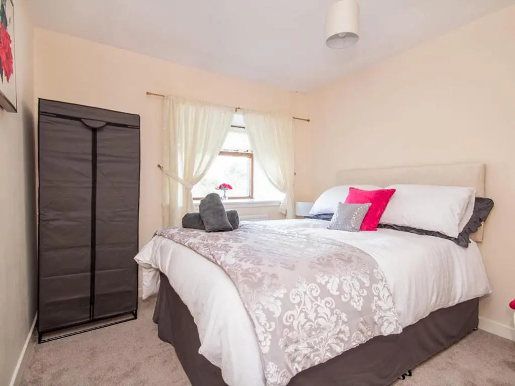 a bedroom with a large bed and a window at Black Rock Cottage in Culbokie