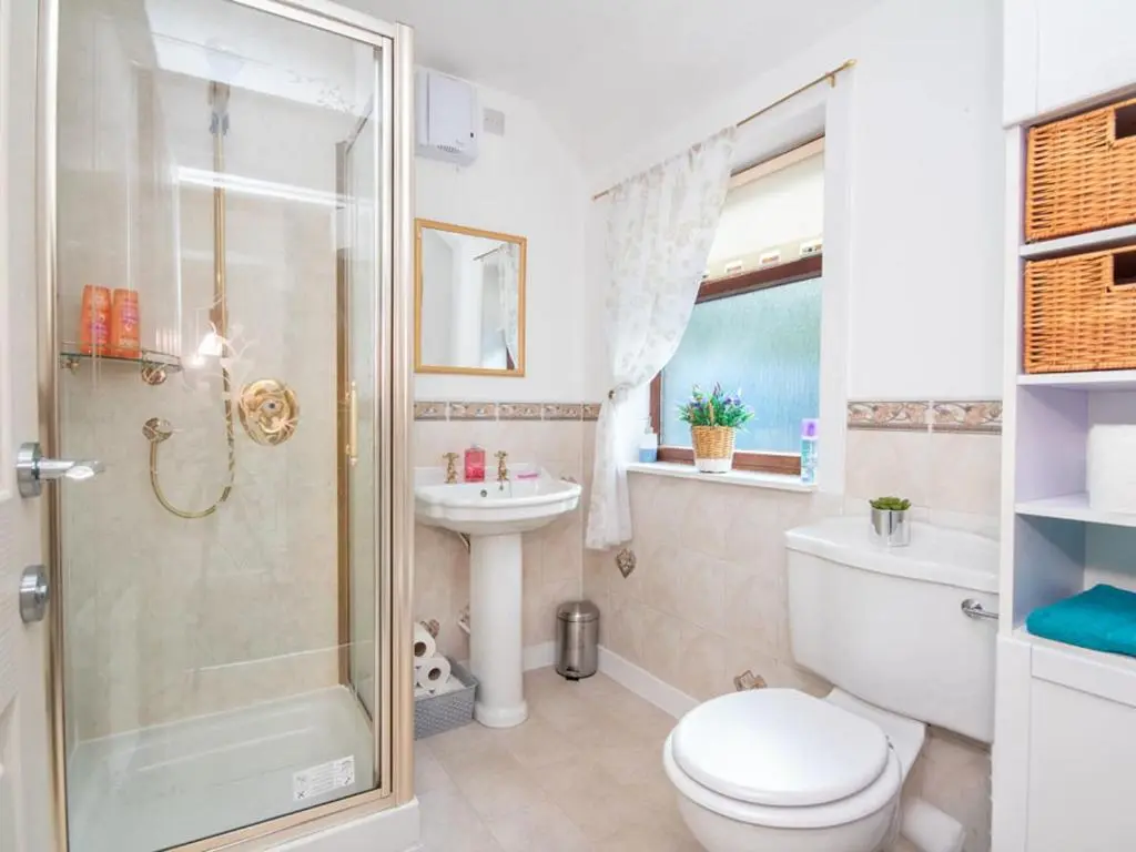 a bathroom with a shower and a toilet and a sink at Black Rock Cottage in Culbokie