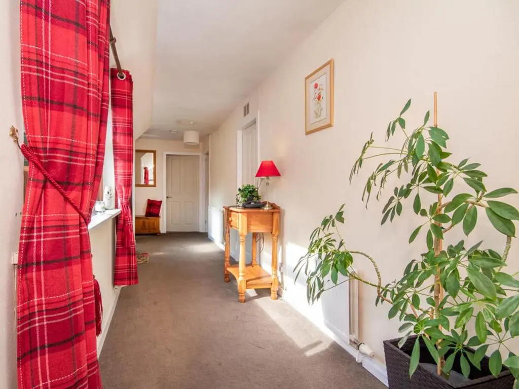 a hallway with a red plaid curtain and a plant at Black Rock Cottage in Culbokie