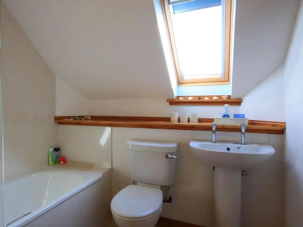a bathroom with a toilet and a sink and a window at The Old Chandlery in Avoch