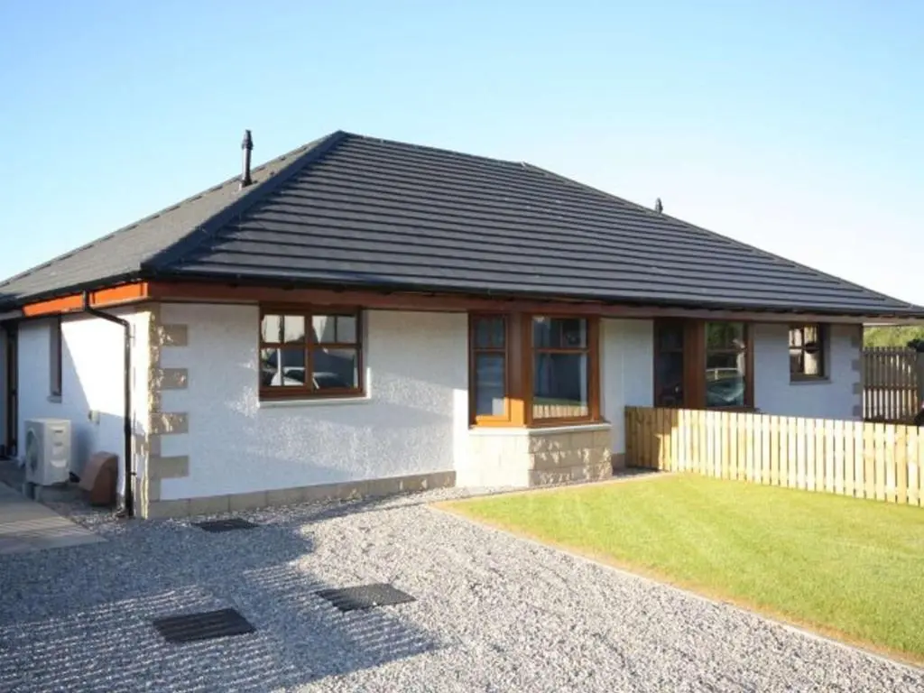 a small white house with a lawn in front of it at Wards Croft No14 in Muir of Ord
