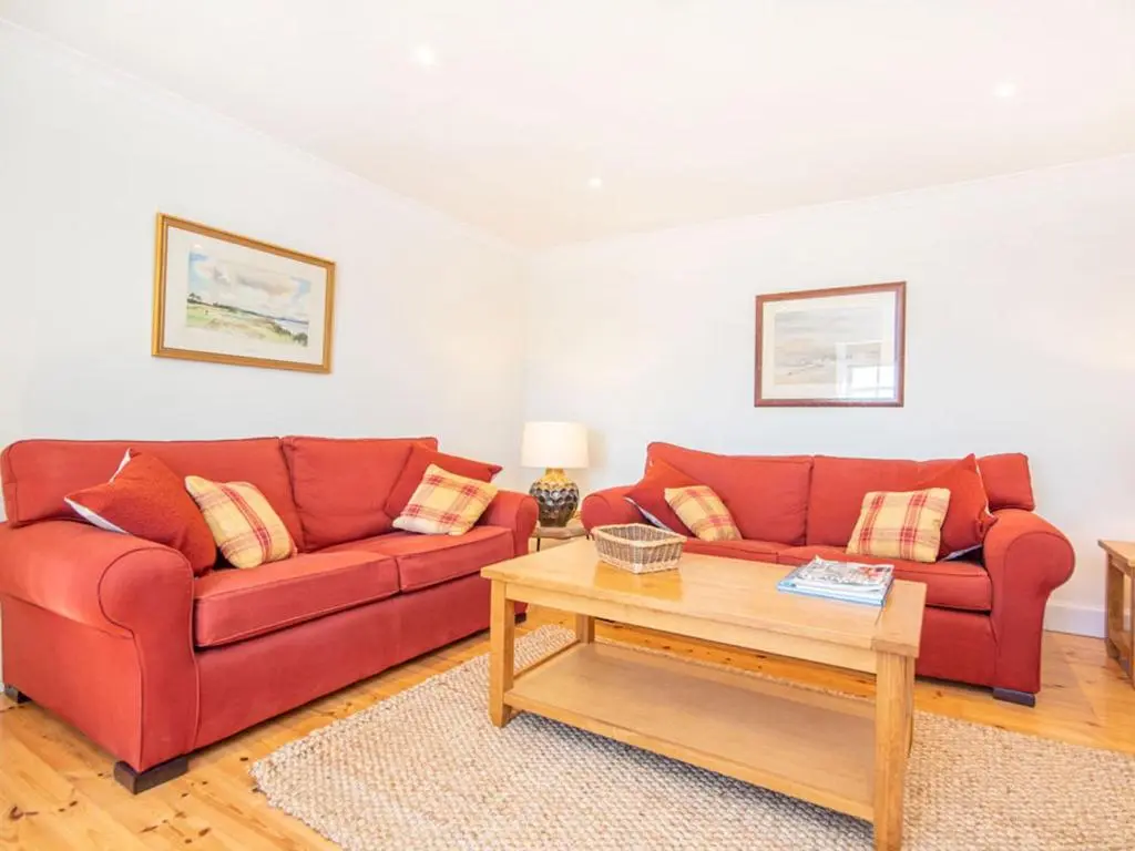 a living room with two red couches and a coffee table at Braefoot in Fortrose