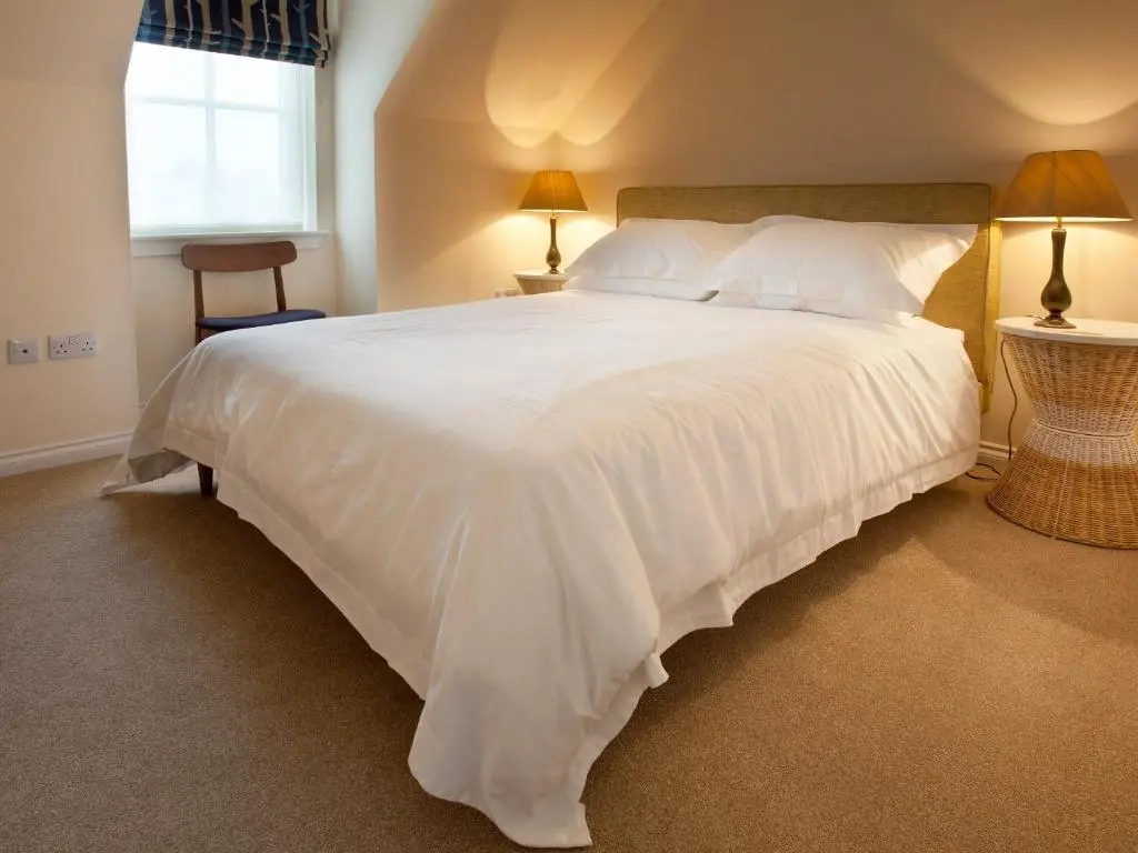 a large white bed in a bedroom with two lamps at Mackay Road - Uk7451 in Dornoch