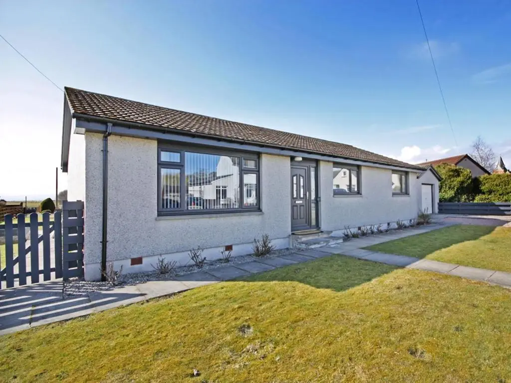 a white house with a fence and a yard at Raasay in Dornoch