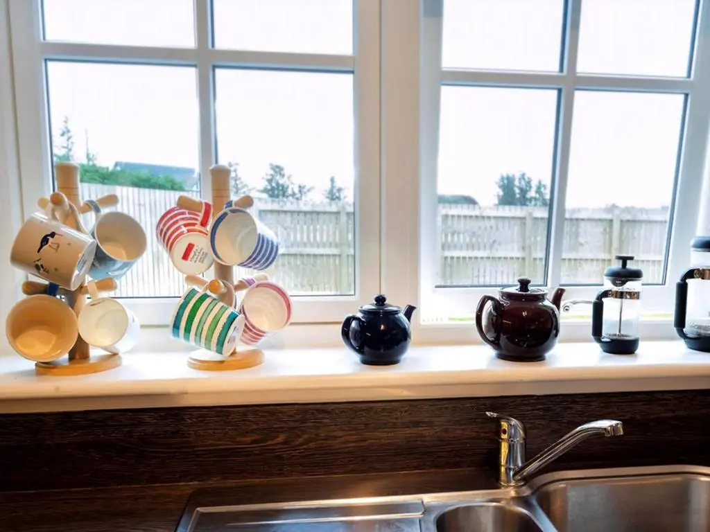 a kitchen counter with cups and a sink and windows at Grant Crescent in Dornoch
