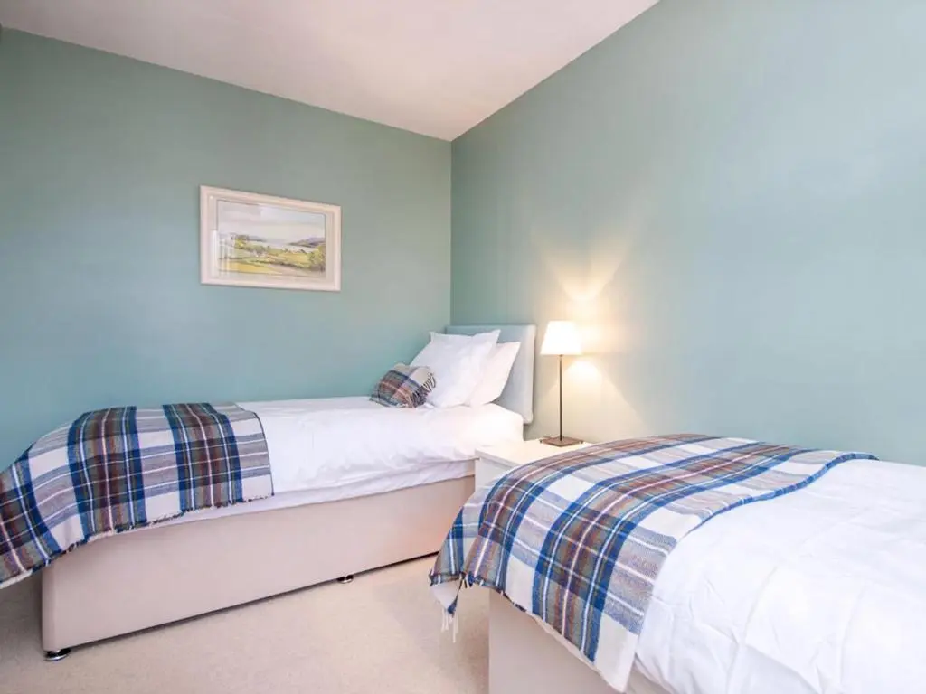 two beds in a bedroom with blue walls at Strathy in Dornoch